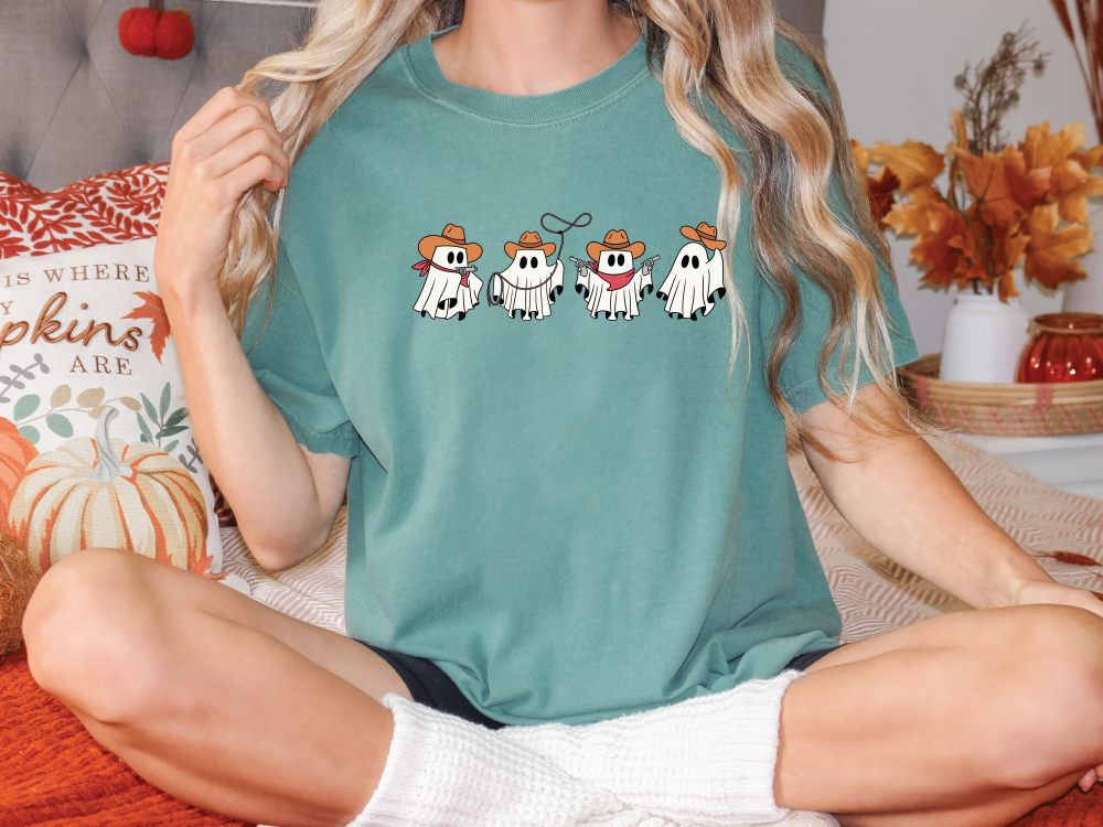 a woman sitting on a bed with three cows on her shirt