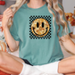 a woman sitting on a bed wearing a t - shirt with a smiley face on