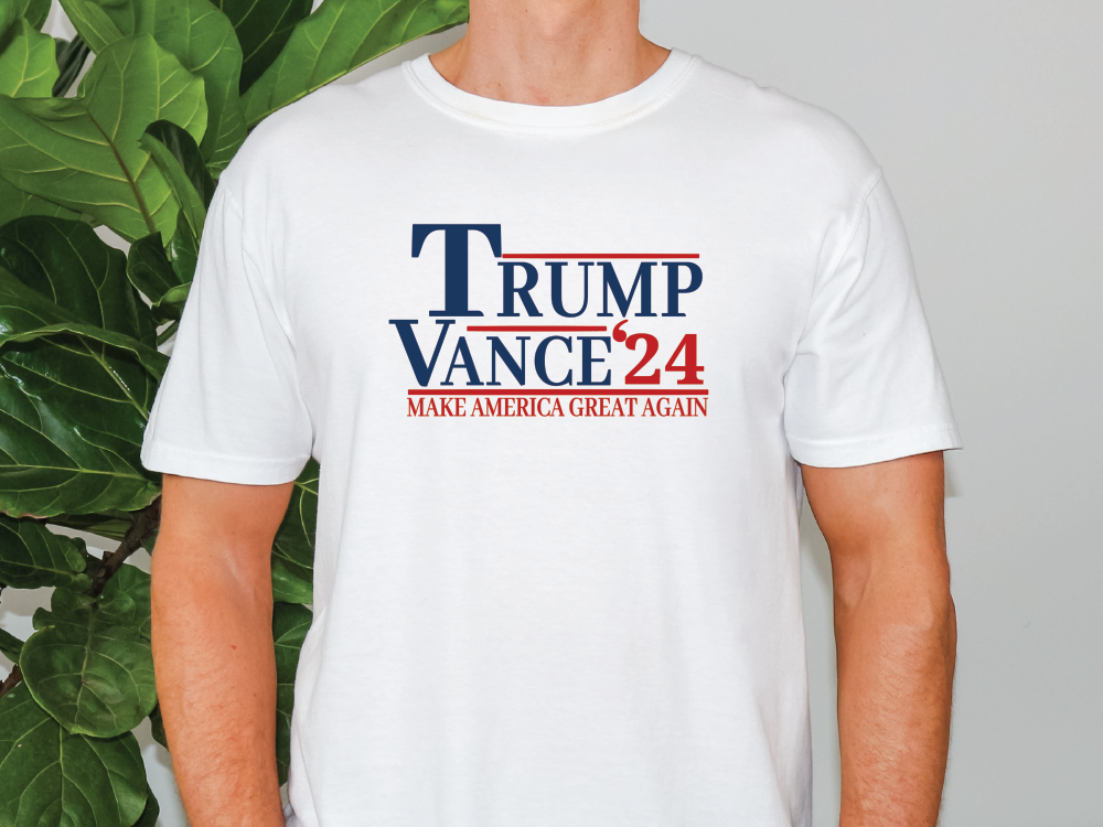 a man wearing a trump t - shirt in front of a plant