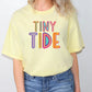 a woman wearing a yellow tiny tide t - shirt