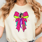 A woman wearing a white t-shirt with a colorful graphic design featuring a stylized female figure with a large pink bow on her head.