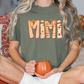 A person sitting on a bed with a pumpkin-themed t-shirt and holding a pumpkin-shaped mug.