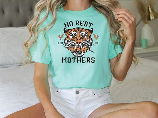 a woman sitting on a bed wearing a t - shirt with a tiger on it