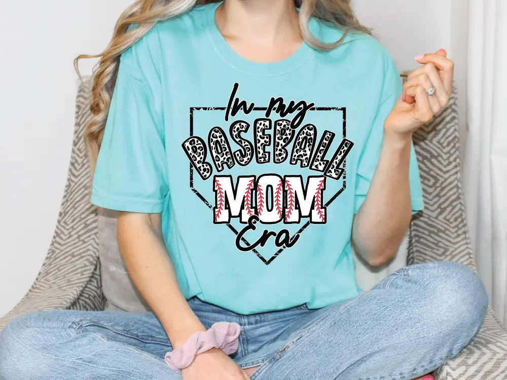 a woman in a baseball mom shirt sitting on a couch