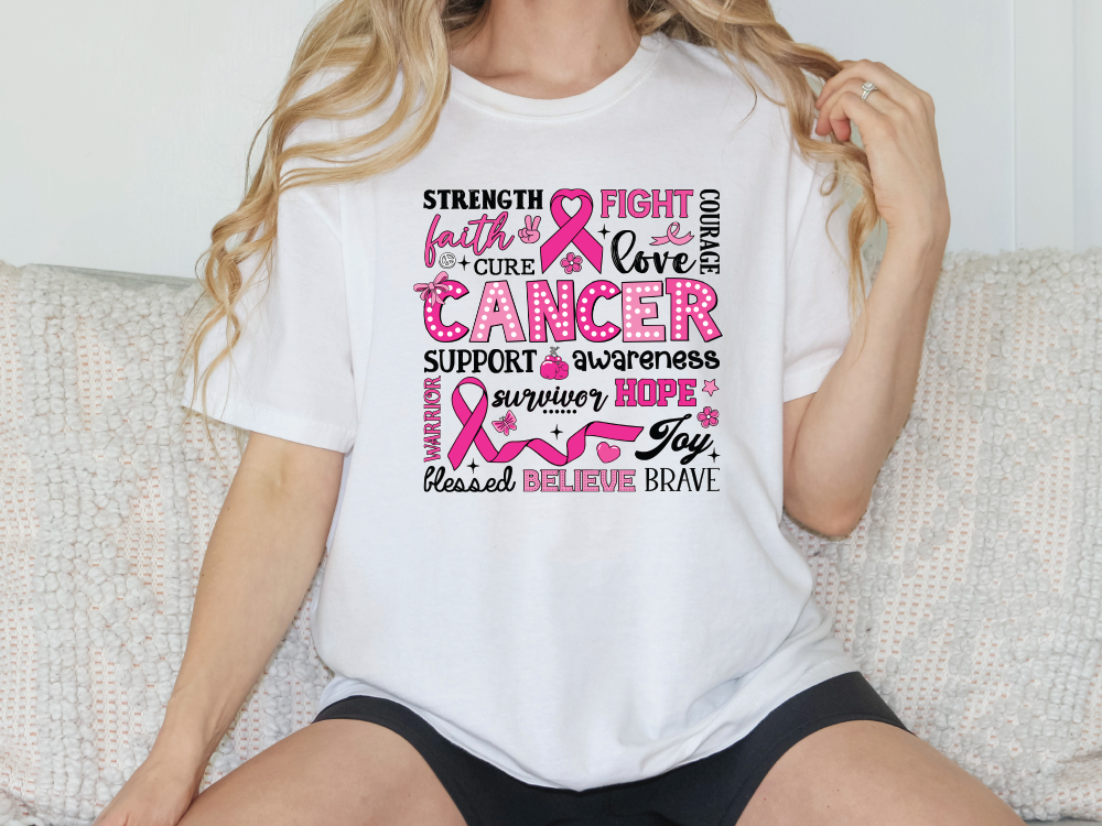 a woman sitting on a couch wearing a t - shirt with a pink ribbon