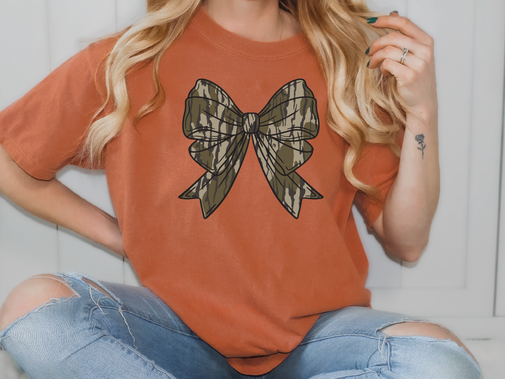 a woman sitting on the floor wearing a t - shirt with a bow on it