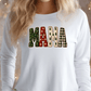 A woman wearing a white long-sleeved shirt with the word "MAMA" printed on it in a festive, holiday-themed font.