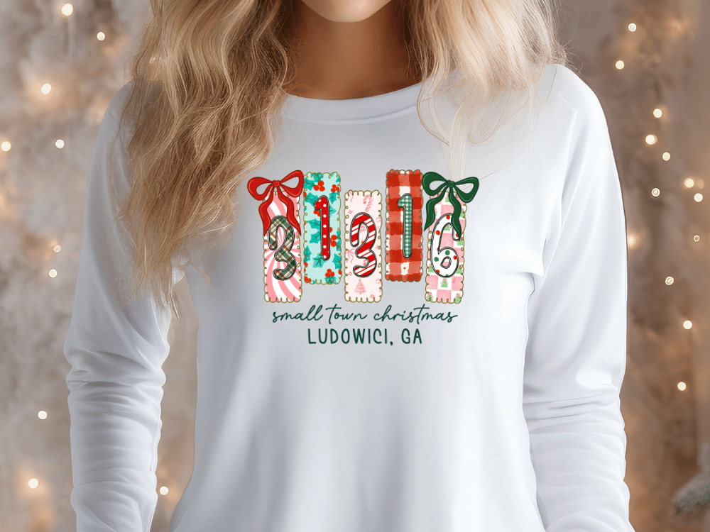 A woman wearing a white long-sleeved shirt with a graphic design featuring the numbers 1, 2, 3, and 4 arranged in a row, along with the text "small town christmas LUDOWIC, GA".