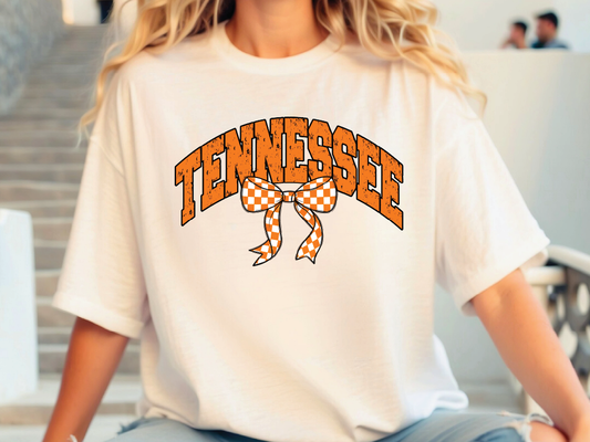 A person wearing a white t-shirt with the word "TENNESSEE" and a checkered bow printed on it.