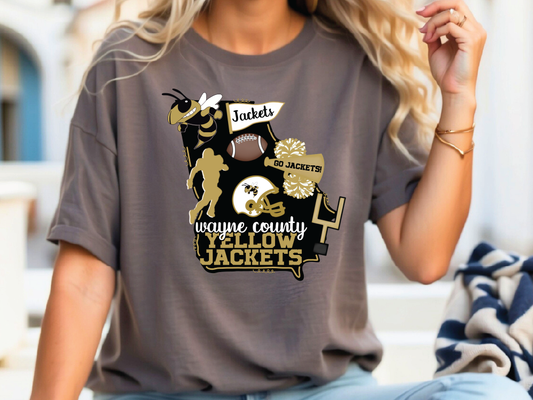 A woman wearing a gray t-shirt with a graphic design featuring various sports-related elements, including a bee, football, and cheerleaders.
