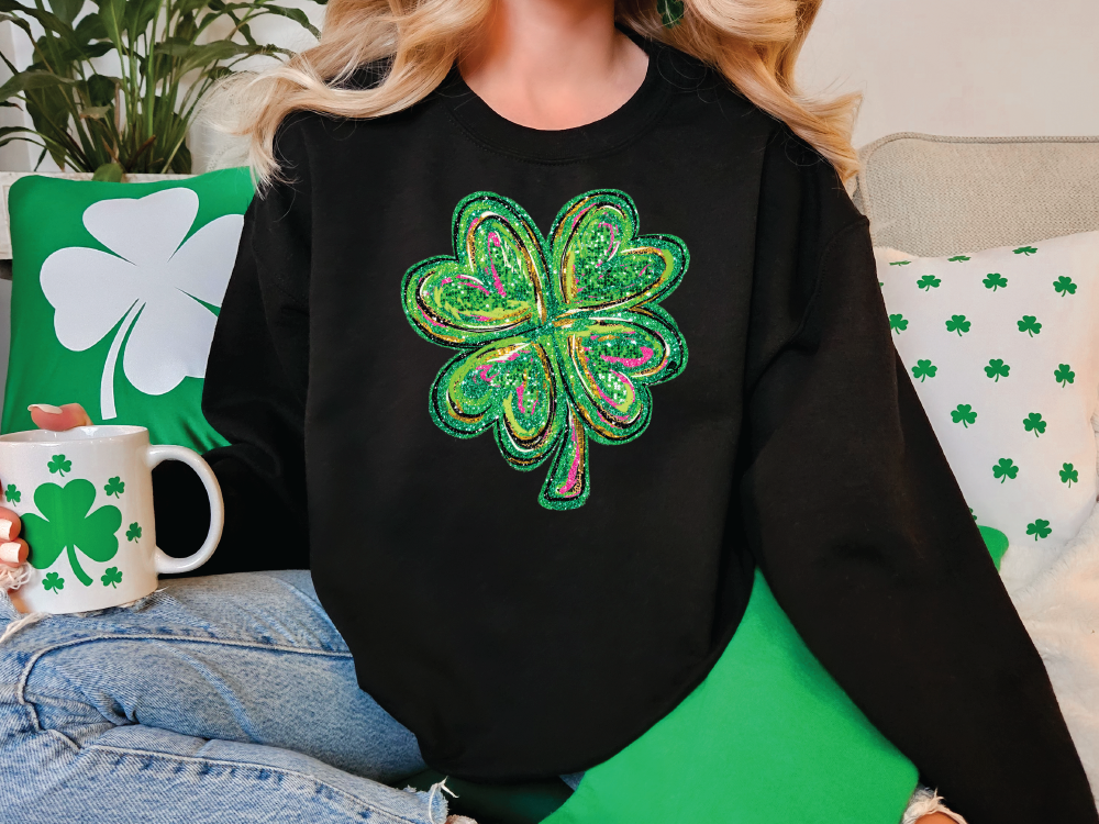 a woman sitting on a couch wearing a black sweater with a green shamrock on it