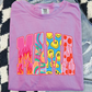 A pink t-shirt with a colorful graphic design featuring the word "MAMA" in a stylized font.