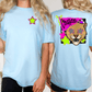two women wearing light blue t-shirts with a graphic design on the back.