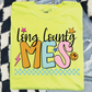 A yellow t-shirt with colorful text and graphics printed on it, placed on a checkered surface.