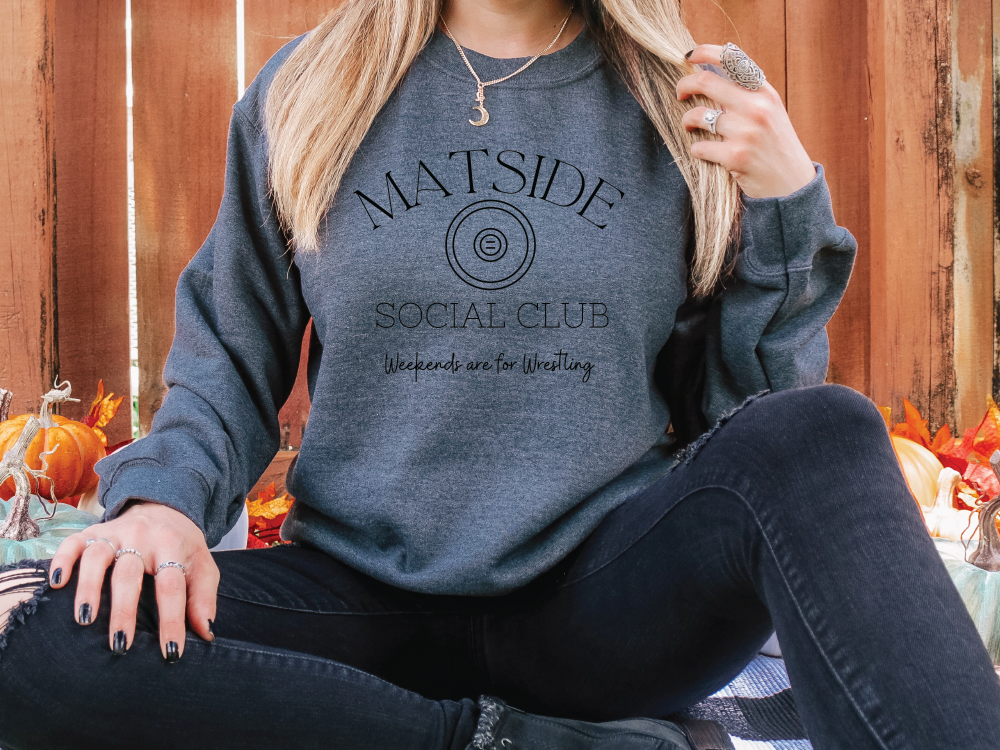 a woman sitting on the ground wearing a grey sweatshirt