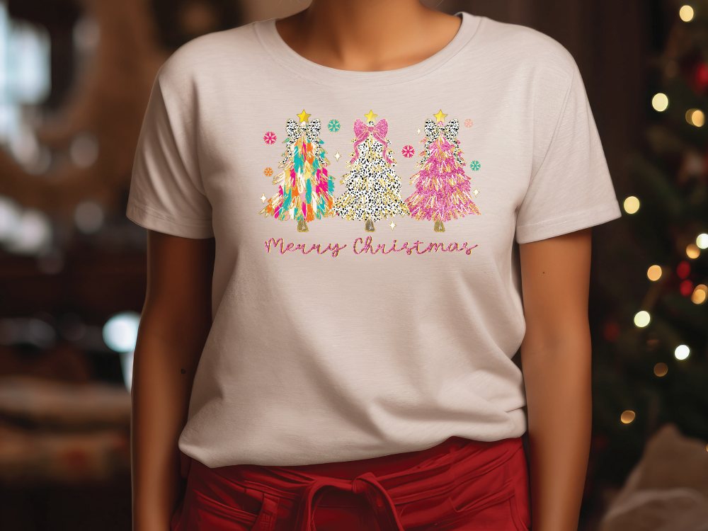 a woman wearing a merry christmas t - shirt in front of a christmas tree