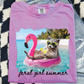A pink t-shirt with a graphic design depicting a raccoon wearing sunglasses and floating on a pink flamingo in a tropical beach setting.