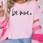 a woman wearing a pink shirt that says be mine