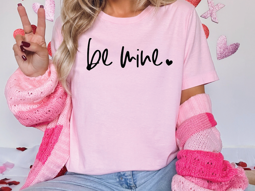 a woman wearing a pink shirt that says be mine