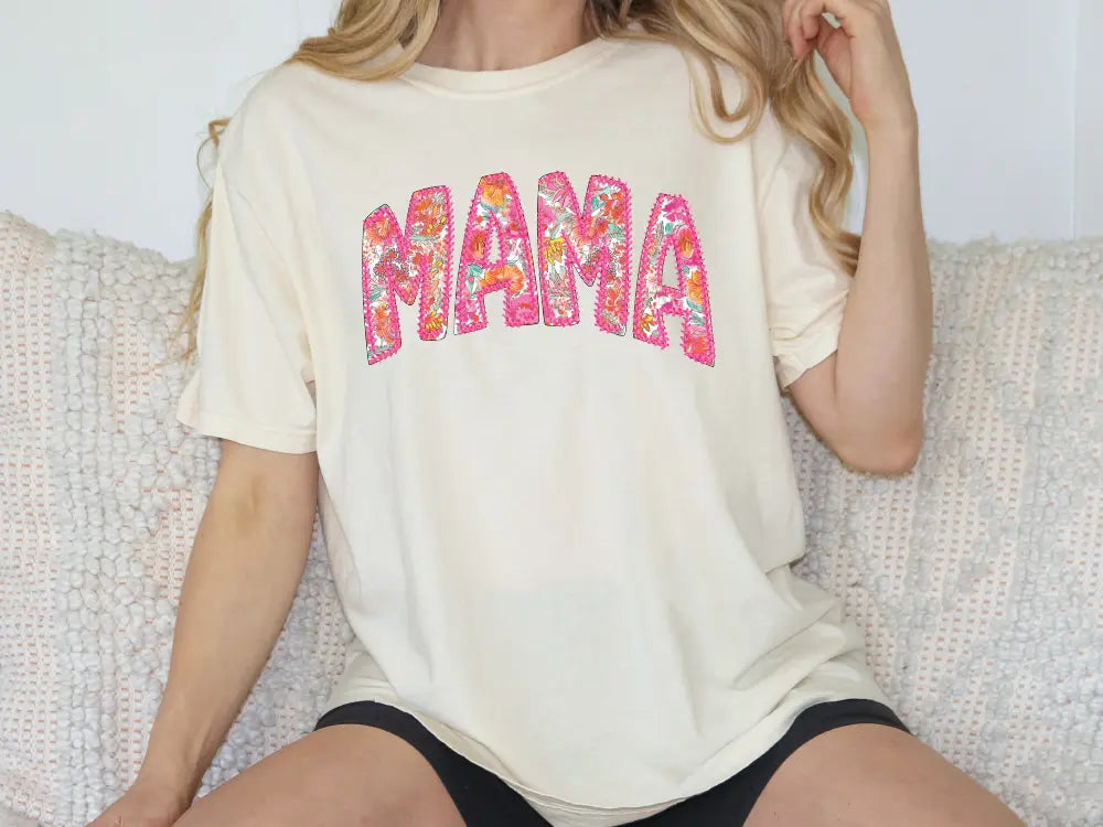 a woman sitting on a couch wearing a shirt that says mama