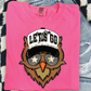 A pink t-shirt with a graphic design of an owl wearing sunglasses and a hat with the text "LET'S GO" printed on it.