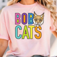 A woman wearing a pink t-shirt with the text "BOBCATS" printed on it, along with a cartoon image of a bobcat.