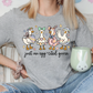 A woman wearing a gray t-shirt with a graphic of four cartoon ducks and the text "Just an egg-cited goose" is sitting on a couch, holding a green mug.