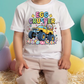 A child wearing a white t-shirt with a colorful graphic of a yellow truck with large tires and a bunny on the back, surrounded by Easter eggs.