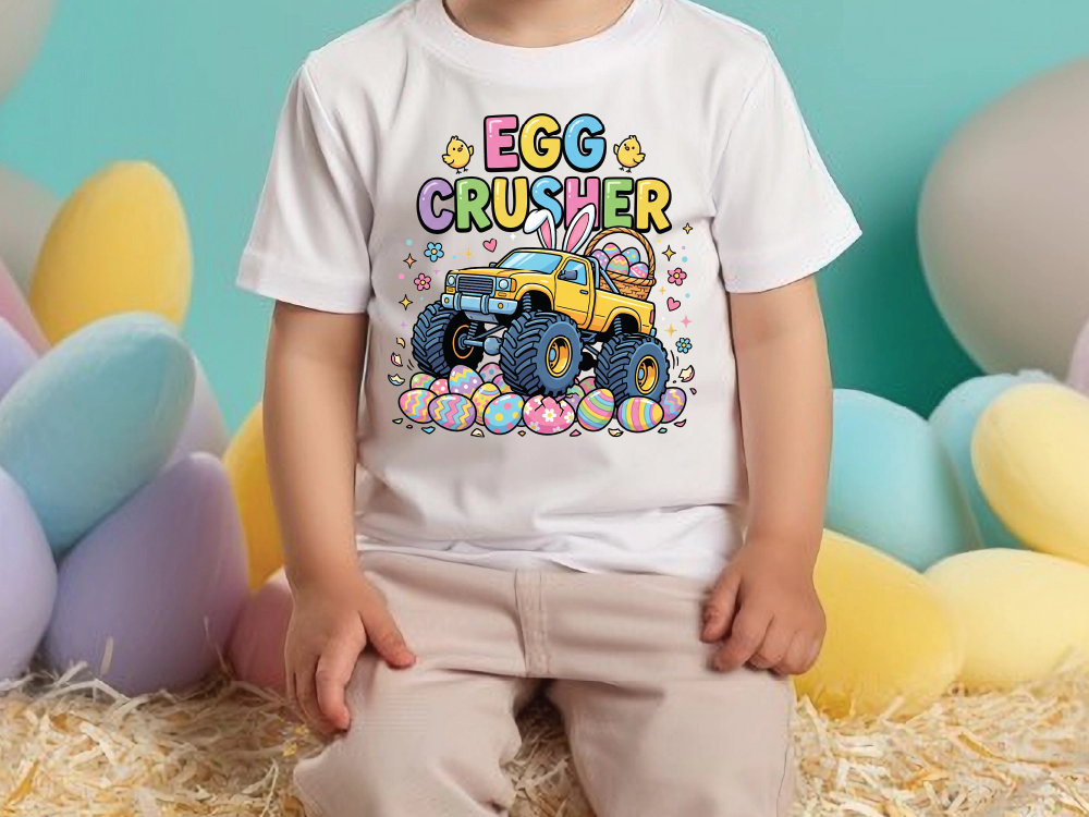 A child wearing a white t-shirt with a colorful graphic of a yellow truck with large tires and a bunny on the back, surrounded by Easter eggs.