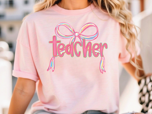 a woman wearing a pink teacher shirt with a bow