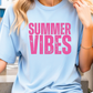 a woman sitting on a ledge wearing a blue shirt that says summer vibes