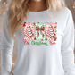A woman wearing a white long-sleeved shirt with a Christmas-themed graphic design on it.