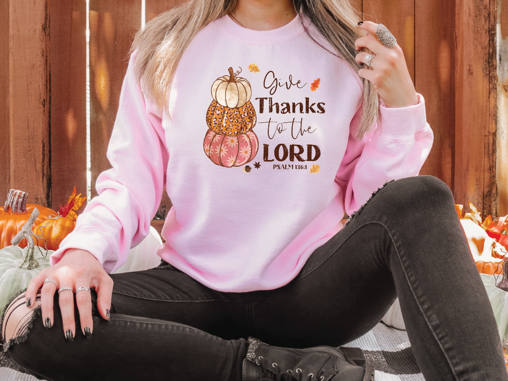 a woman sitting on the ground wearing a pink thanksgiving sweatshirt