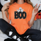 a woman in an orange boo shirt sitting on a bed