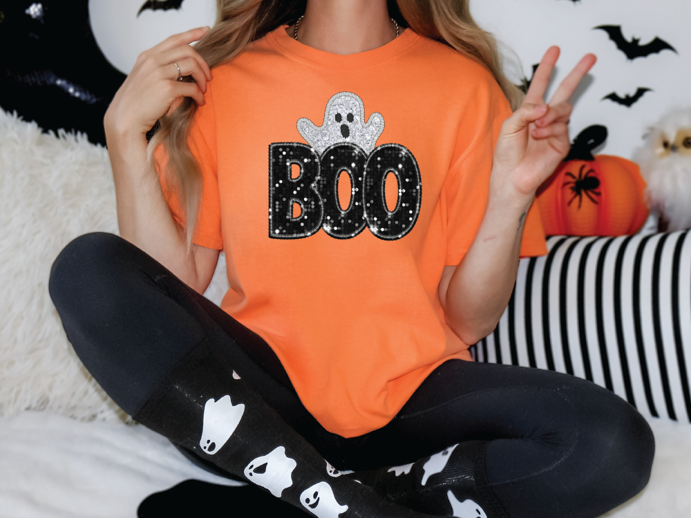 a woman in an orange boo shirt sitting on a bed