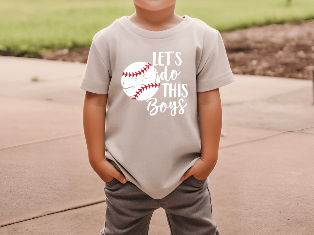 A young boy wearing a t-shirt with the text "LET'S DO THIS BOYS" printed on it.