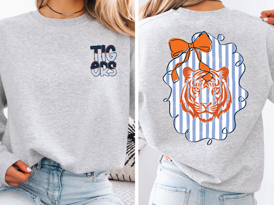 a person wearing a grey sweatshirt with a tiger graphic on the back.