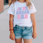 a little girl standing on a sidewalk wearing a shirt that says in my cheer era