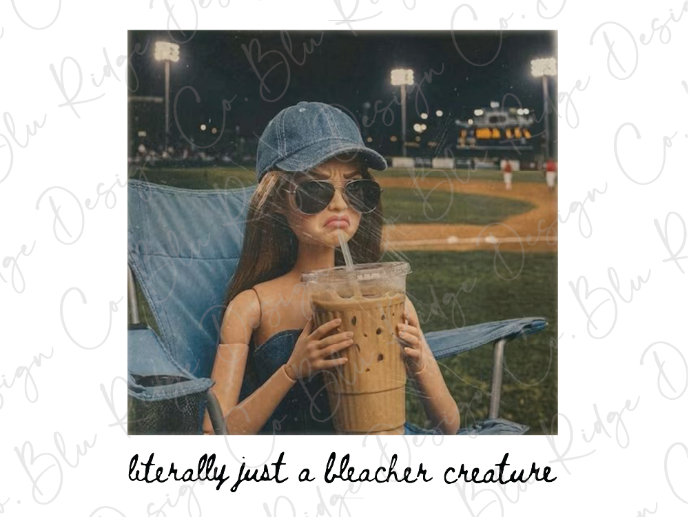 A doll wearing a blue cap and sunglasses is sitting in a chair, holding a large drink in a plastic cup.