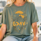 A woman wearing a green t-shirt with a graphic design featuring mountains, sun, and flowers.