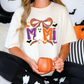 A woman wearing a white t-shirt with a graphic design of a ghost and a pumpkin, holding a mug in her hands.