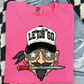 A pink t-shirt with a cartoon pirate face and a pirate hat, along with a pair of jeans and a checkered patterned rug.