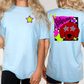 A woman wearing a light blue t-shirt with a graphic design on the back, including a red dog wearing sunglasses and a star.