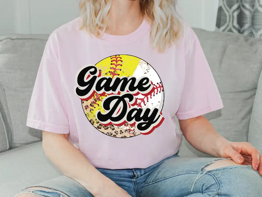 a woman sitting on a couch wearing a game day t - shirt