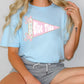 A woman wearing a light blue t-shirt with a pink and white flag design and the text "Blue Tide" on it.
