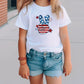 a little girl wearing a white shirt with a peace sign on it