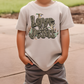 A child wearing a white t-shirt with the text "Love is like Jesus" printed on it.