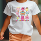 a little girl walking down a street wearing a white shirt with cartoon characters on it