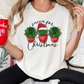 A person wearing a white t-shirt with a graphic design of three potted succulents and a Santa hat, holding a red mug with the text "oh what fun!"