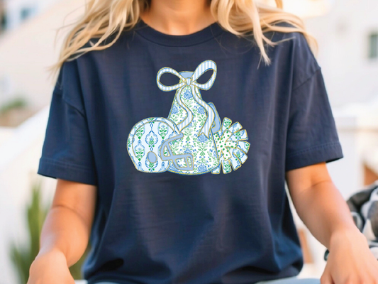 A woman wearing a navy blue t-shirt with a graphic design of a blue and white patterned bag with a bow on it.